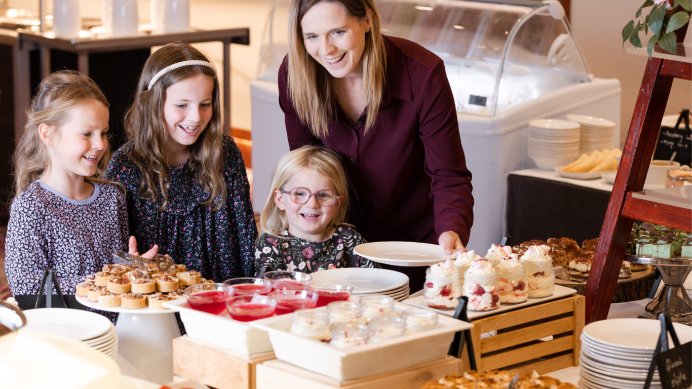 Family enjoying dessert buffet with cakes and fruit at hotel&rsquo;s delightful dining area. Welcoming for guests of all ages.
