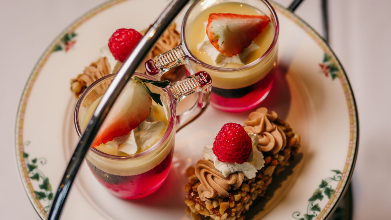 Exquisite afternoon tea with colourful desserts and fresh fruit on elegant china, inviting guests to a delightful hotel experience.