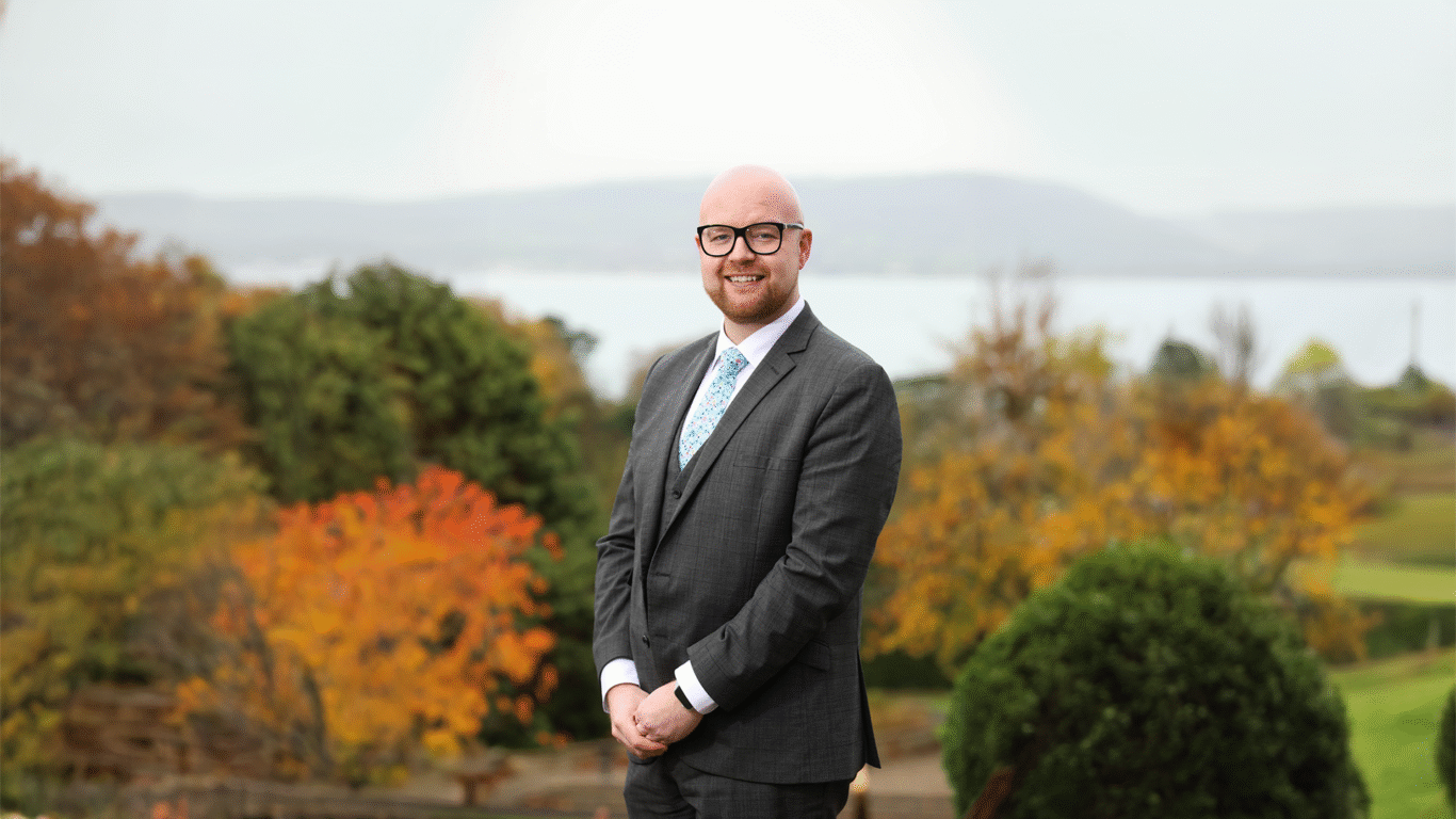 Scott Weatherup, from Hastings Hotels poses in front of a autumnal landscape.