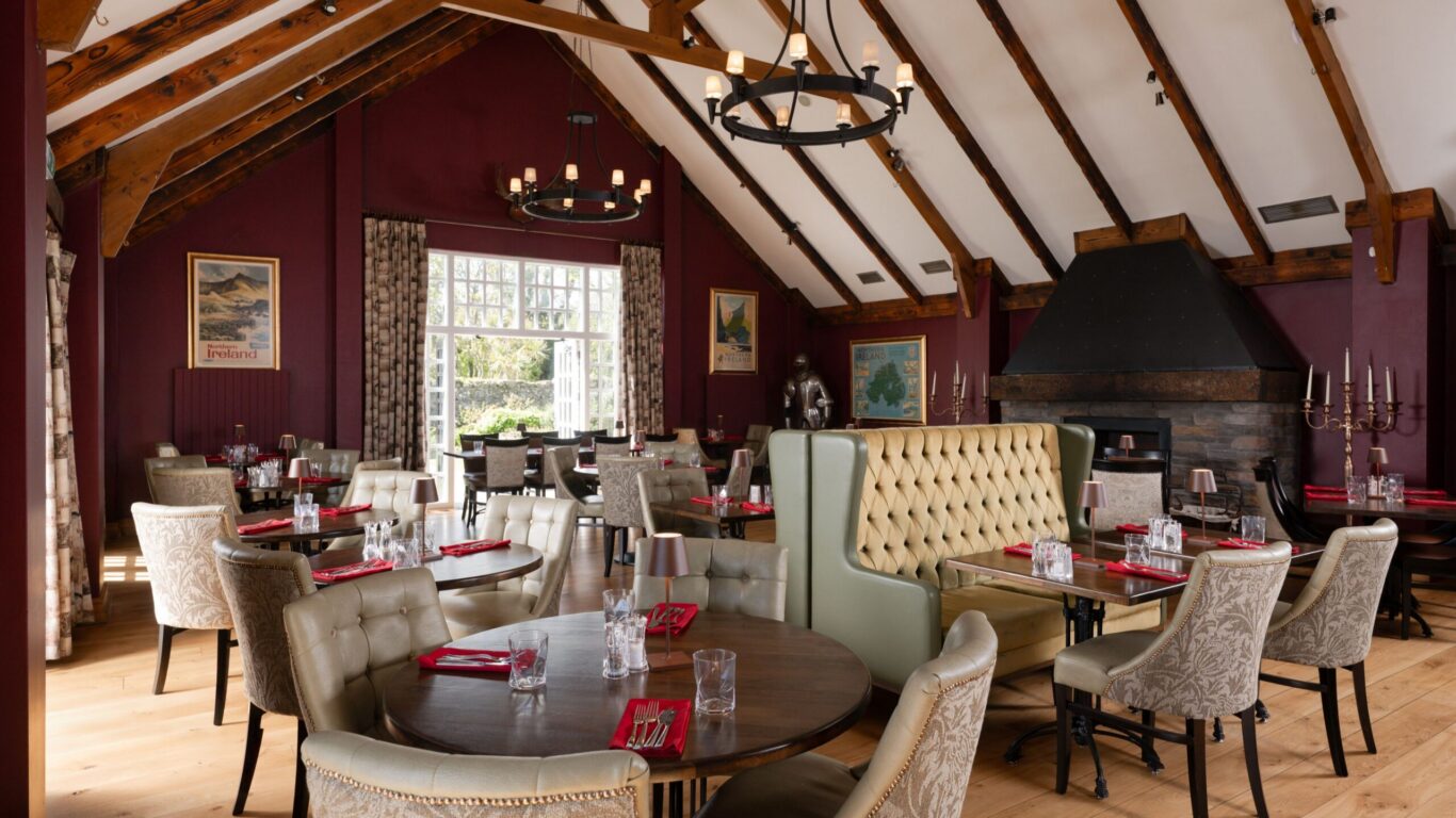 Cosy dining room with elegant decor, wooden beams, plush seating, and a warm fireplace in a charming hotel setting.