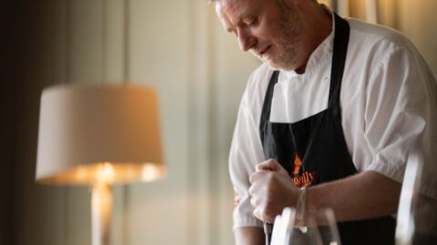 Chef expertly carves roast in elegant hotel dining room, creating a warm, inviting atmosphere with refined cuisine.